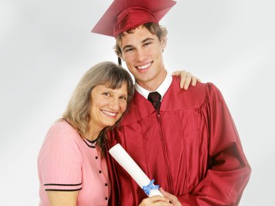 Graduate posing in cap and gown with his proud mother.  Isolated on white.